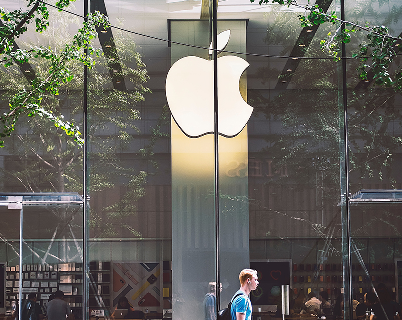 Man walking past Apple Store Window with Brand Mark in background